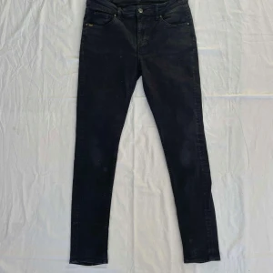 Svarta jeans från Tiger of Sweden - Säljer ett par svarta jeans från Tiger of Sweden. Byxorna har klassisk femficksdesign, knapp- och dragkedjegylf samt smal passform hela vägen ner. Perfekta för dig som gillar stilrena jeans