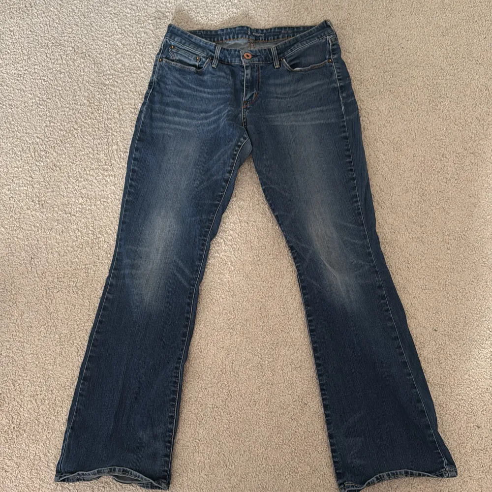 Snygga blå bootcut jeans med klassisk femficksdesign och knappgylf. Perfekta för en avslappnad stil med en touch av retro. De har en lätt tvättad look som ger en cool vintagekänsla.. Farkut & Housut.