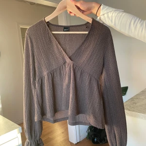 Blus - Säljer en snygg brun blus med ribbad struktur och v-ringning. Perfekt för en stilren look! Tröjan är tunn så passar nu till våren/sommaren. Använd en gång💕