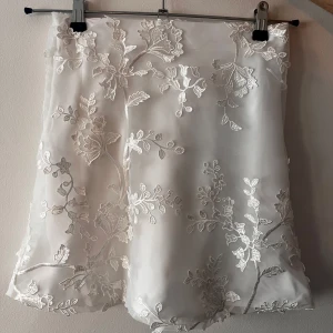 Vit kjol med blommigt mönster från Bik Bok - Säljer en elegant vit kjol från Bik Bok med vackert blommigt mönster. Kjolen har en fin struktur och är perfekt för speciella tillfällen. Den är i storlek XS och har en stilren design som passar till många olika toppar.