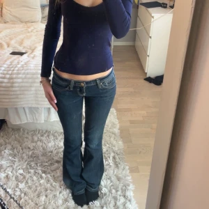 Mörkblå bootcut jeans - Snygga mörkblå bootcut jeans med perfekt låg midja. Jeansen har dekorativa sömmar och fina detaljer där bak!! As fin mörkblå färg dessutom!