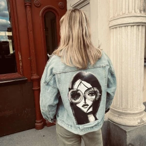 AMORA 002 - Jeansjacka från JAQUÍ med trycket AMORA 002 Ärmlängd (från armhåla): 42 cm Byst: 58 cm Längd: 55 cm Storlek: L Modellen är 167 cm lång.