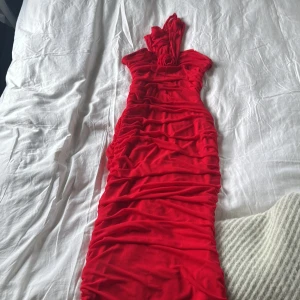 Röd klänning från Shein - Snygg röd klänning från Shein med en tight passform. Klänningen har en elegant rynkad design och är ärmlös, perfekt för en festlig kväll. Den är tillverkad i ett mjukt och stretchigt material som ger en bekväm känsla.OBS No free shipping , går ej att ta bort , aldrig använd , lappen kvar 