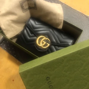 Svart quiltad axelväska från Gucci - Säljer en elegant svart axelväska från Gucci med quiltat mönster och en gyllene kedja. Väskan har en framträdande GG-logga i guld på framsidan. Perfekt för att ge din outfit en lyxig touch. Har även kvitto o allting de bara o skriva för mer bilder 