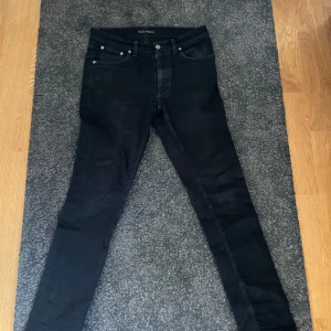 Svarta jeans från Nudie Jeans - Snygga svarta jeans från Nudie Jeans med en klassisk femficksdesign. De har en slim passform och är tillverkade i ett slitstarkt material. Perfekta för en stilren look. Hör av er vid frågor😄