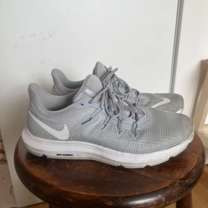 Grå Nike löparskor storlek 39 - Säljer ett par grå Nike löparskor med vit sula och snörning. Skorna har en stilren design med Nike-loggan på sidan och är perfekta för löpning och träning. Fina i skick. 
