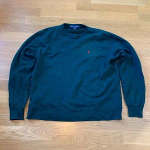 Grön sweatshirt från Ralph Lauren - Säljer en klassisk grön sweatshirt från Ralph Lauren med en liten röd logga på bröstet. Tröjan har långa ärmar och rund halsringning. Perfekt för en avslappnad stil. Utmärkt skick storlek M.