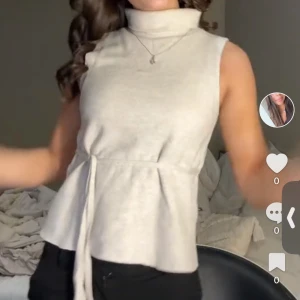 Polotröja från Zara - Snygg beige ärmlös polotopp med knytband i midjan. Perfekt för en stilren look, oavsett tillfälle. Toppen har en hög krage som ger en elegant touch.