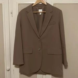 Beige kavaj  - Snygg beige kavaj från H&M! Rak design som har en lite oversized passform och två knappar framtill! Aldrig använd! Nypris: 399kr