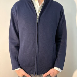Mörkblå kofta med dragkedja - Snygg mörkblå kofta från Max Men med dragkedja framtill. Den har en enkel design med ribbade muddar och två fickor. Perfekt för en stilren look. Plagget är i bra skick, men något nopprig. Modellen är 182cm/67kg