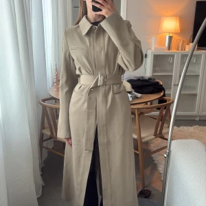 Beige trenchcoat med bälte - Beige trenchcoat med bälte i midjan från Lovisa Worge x nakd. Har en ”scarf” man kan ta av och på, som syns på bilderna. Slutsåld! Använd en gång 🥰