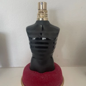 Jean Paul Gaultier Le Male Le Parfum - Elegant parfymflaska formad som en manlig torso i svart med guldiga detaljer. Förpackningen är en stilren, svart metallburk med guldtext. Perfekt för den som vill ha en sofistikerad och maskulin doft.