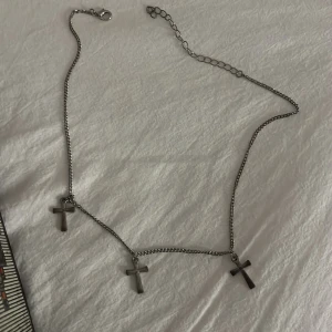 Halsband med korshängen - Snyggt halsband i silverfärg med tre korshängen. Perfekt för att ge en stilren touch till din outfit. Justerbar kedja för perfekt passform.