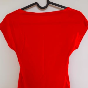 Röd  topp med djup rygg - Stretchig röd topp med slimmad passform och djup rygg. Perfekt för fest eller en utekväll. Använd en gång, jättefint skick!