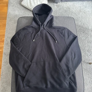 Svart hoodie från Lanvin - Säljer en stilren svart hoodie från Lanvin. Den har en klassisk design med justerbar huva och en stor ficka framtill. Perfekt för en avslappnad look.pris kan diskuteras köpt på care of Carl 