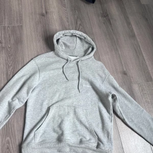 Grå hoodie från Carhartt - Säljer en stilren grå hoodie från Carhartt med broderad logga på bröstet. Tröjan har en klassisk känguruficka och justerbar huva med dragsko. Perfekt för en avslappnad stil.