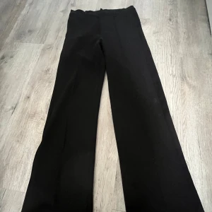 Svarta kostymbyxor från Kappahl - Säljer ett par klassiska svarta kostymbyxor från Kappahl. De har en rak passform och är perfekta för en stilren look. Byxorna är tillverkade i ett mjukt material som ger en bekväm känsla hela dagen. Kostymbyxorna har en rak söm på båda benen för att styla upp dom lite! Super fina och jättesköna!