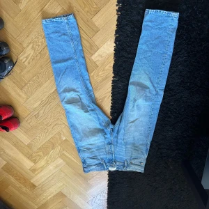 Blå jeansbyxor - Säljer ett par klassiska blå jeansbyxor med normal passform. De har en traditionell femficksdesign och stängs med dragkedja och knapp. Perfekta för en avslappnad stil.