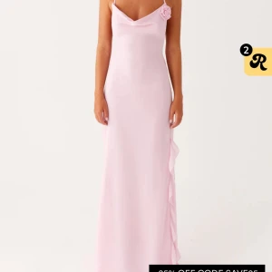 Rosa långklänning/balkläning  - Elegant ljusrosa långklänning med smala axelband och en vacker blomdetalj vid axeln. Klänningen har volangdetaljer längs sidan och en mjuk, flytande passform. Passar Såå fint till balen!!! 