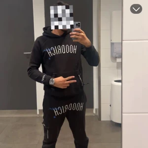 Hoodrich trucksuit  - Säljer en svart hoodie från Hoodrich med vit text på bröstet och såklart mjukisarna med. Hoodien och mjukisarna har en klassisk design med långa ärmar och en bekväm passform. Perfekt för en avslappnad stil. OBS!! Ny pris 1500 