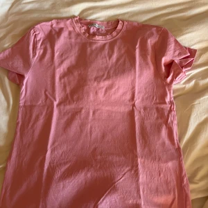 Rosa t-shirt från Zara - Säljer en enkel och stilren rosa t-shirt från Zara. Perfekt för en avslappnad look. T-shirten är kortärmad och gjord i mjuk bomull. Passar perfekt till jeans eller shorts för en casual stil.