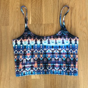 Mönstrad linnetopp från BikBok XS - Färgstark linnetopp från BikBok i storlek XS med smala axelband. Toppen har ett unikt, färgglatt mönster i blått, orange, svart och vitt. Materialet är ribbat och stretchigt, perfekt för en cool och avslappnad look.
