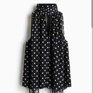 Svart prickig ärmlös blus med scarf - Snygg svart blus med vita prickar och tillhörande scarf runt halsen. Slutsåld på HMs sida! Nyskick och har alla lappar kvar. 