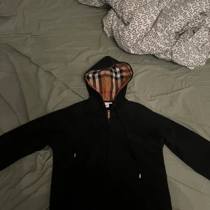 Svart Burberry hoodie med klassisk luva - Svart hoodie från Burberry med dragkedja och luva aldrig andvänd. Säljer pga den är är för liten 