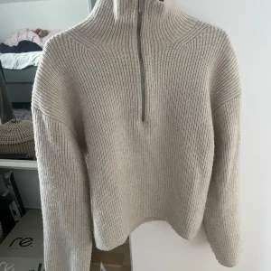 Beige stickad half zip-tröja H&M XS - Beige ribbstickad tröja från H&M i storlek XS. Tröjan har hög krage och en snygg half zip-dragkedja framtill. 