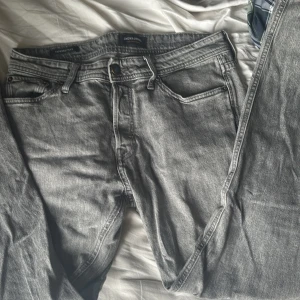 Grå tapered jeans Jack & Jones 29/32 - Snygga grå jeans från Jack & Jones i modellen Tapered Mike. Jeansen har en tapered passform med klassiska fem fickor och dragkedjegylf. Perfekta för dig som gillar en avslappnad men ändå stilren look. Nypris runt 800kr