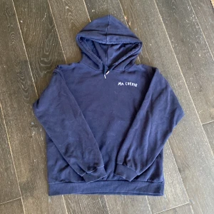 Marinblå hoodie Ma Chérie Gina Tricot - Mysig marinblå hoodie från Gina Tricot med texten 'Ma Chérie' broderad fram och bak samt två hjärtan på ryggen. Klassisk huva och långa ärmar, perfekt för chill dagar. Tillverkad i mjuk bomullsmix.
