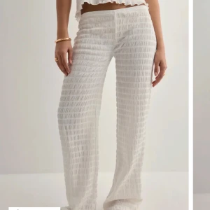 Vita vida linnebyxor med struktur - Säljer ett par vita linnebyxor med snygg struktur och relaxed fit. Byxorna har hög midja och vida ben, perfekta för en chill och trendig sommarlook. Lätta och luftiga, passar grymt till crop tops eller linnen. Pris kan diskuteras