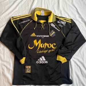 Sällsynt AIK 98/00-tröja – Strl S - Letar efter ett nytt hem till min AIK-tröja från 98/00. Det är den gamla Adidas-modellen med “Maroc Läskigt Gott!” – äkta original, ingen nytryckt variant. 	•	Storlek S (svår att hitta i den här storleken) 	•	Broderat klubbmärke, snygg passform 	•	Använt skick  Riktigt fin retrotröja, perfekt för samlare eller för att flexa på match. Prisidé: ca 1100–1400 kr, men kan diskuteras. Skriv om du är intresserad!