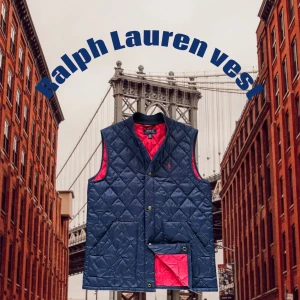 Mörkblå quiltad dunväst Ralph Lauren - Quiltad mörkblå dunväst från Ralph Lauren med röd insida och klassisk Polo-logga på bröstet. Västen har tryckknappar framtill, två stora fickor och en snygg kontrast mellan ytter- och innertyg. Perfekt lager-på-lager-plagg med sportig känsla.