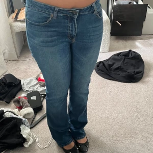 Blå bootcut jeans med broderade fickor - Säljer ett par klassiska blå jeans med bootcut passform och snygga broderade detaljer på bakfickorna. Jeansen har normal midja och är tillverkade i mjukt denimtyg som sitter skönt hela dagen.