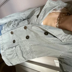 Ljusgrön skepparkavaj  - Snygg ljusgrön skepparkavaj från H&M med dubbla knapprader, flera fickor och cool broderad detalj på ena fickan. Jackan har klassisk krage och är tillverkad i bomull, perfekt för dig som gillar en chill men stilren look.