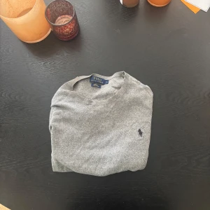 Grå slim fit tröja från Polo Ralph Lauren - Säljer en grå långärmad tröja från Polo Ralph Lauren i slim fit med klassisk rund hals i ett väldigt bra skick. Tröjan är tillverkad av mjuk pima bomull och har den ikoniska broderade loggan på bröstet. Nypris är ca 1899 mitt pris 649, men priset kan såklart diskuteras.