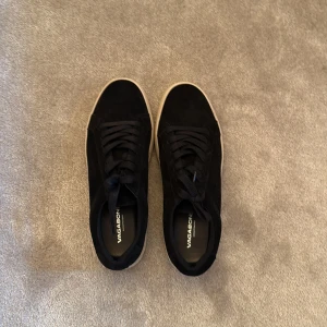 Svarta mockasneakers från Vagabond - Stilrena svarta sneakers från Vagabond i mocka med vita platta sulor och klassisk snörning. Skorna har rund tå och en enkel, clean design som passar till det mesta. Perfekta för dig som gillar en tidlös look med lite edge.