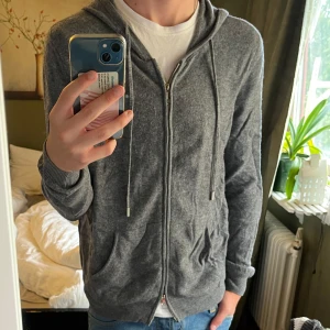 Merinoull zip hoodie - En grå zip-hoodie gjort av superfine merino i storlek Medium, känns likt kaschmir/cashmere. Säljer då den börjar bli för liten. Hör gärna av dig om du har frågor.