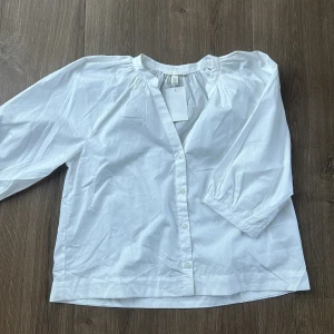 Vit skjorta med puffärm från H&M - Snygg vit skjorta från H&M med puffiga trekvartsärmar och knappar framtill. Skjortan har en avslappnad passform och är tillverkad i mjuk bomull. Perfekt för dig som gillar stilrena och enkla plagg med en twist.
