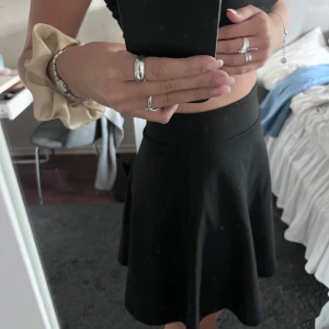 Svart kortkjol från NA-KD - Enkel och stilren svart kortkjol från NA-KD med lätt utsvängd passform och bred midja. Kjolen är i ett mjukt och stretchigt material som sitter snyggt på kroppen