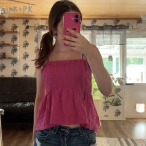 Rosa smockad linnetopp från Shein - Supersöt rosa linnetopp från Shein med smockad överdel och volang nertill. Axelbanden är tunna och knyts på axlarna för en extra gullig touch. Perfekt till jeansshorts eller kjol när det är varmt ute.