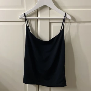 Svart linnetopp från BikBok XS - En stilren svart linnetopp från BikBok i storlek XS. Toppen har tunna axelband och en lätt draperad halsringning som ger en snygg och enkel look. Perfekt att matcha med jeans eller kjol för en trendig outfit.