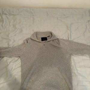 Grå stickad half zip-tröja från Jack & Jones - Säljer en stilren grå stickad tröja från Jack & Jones med half zip-dragkedja och hög krage. Perfekt för lager-på-lager och passar till jeans eller chinos. Tröjan har lång ärm och en klassisk, normal passform.