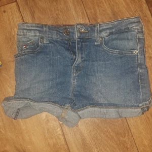 Blå jeansshorts Tommy Hilfiger - Snygga blå jeansshorts från Tommy Hilfiger med klassisk femficksdesign och uppvikta benslut. Säljer för att jag har växt ur dem! Perfekta att ha en varm sommardag!