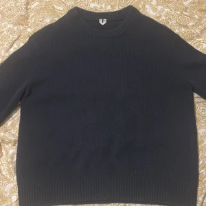 Mörkblå stickad tröja med rund hals - En enkel och stilren mörkblå stickad tröja med rund halsringning och ribbade muddar. Perfekt för lager-på-lager och funkar till både jeans och kjol. Klassisk modell med lång ärm och mjukt material. Från arket original pris 799kr mitt pris 400kr helt ny nästan använd 2 gånger bara rikigt skön och perfekt för vintern. Storlek S