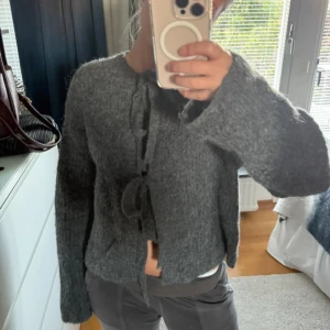 Grå kofta med knyt - Mysig grå kofta från Gina Tricot i fluffigt stickat material. Man kan ha knytena både fram eller bak. Storlek xs.