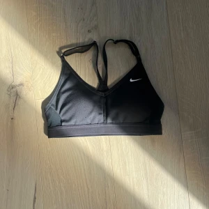 Svart sport-bh från Nike Xs - Svart sport-bh från Nike med smala justerbara axelband och klassisk logga framtill. Snygg och enkel design. Perfekt för träning och aktiva dagar. Säljer pga att den inte passar längre 💗