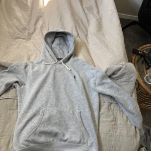 Grå hoodie från Polo Ralph Lauren XS - Säljer en grå hoodie från Polo Ralph Lauren i storlek XS. Tröjan har huva med snörning, magficka och det klassiska lilla Polo-logot på bröstet. Mjuk insida och långärmad, perfekt för chill dagar. Materialet är bomull och polyester.