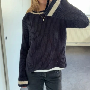 Stickad tröja - Säljer en mörkblå stickad tröja med breda vita ränder vid halsringningen och ärmsluten. Från hunkydory. 100% bomull